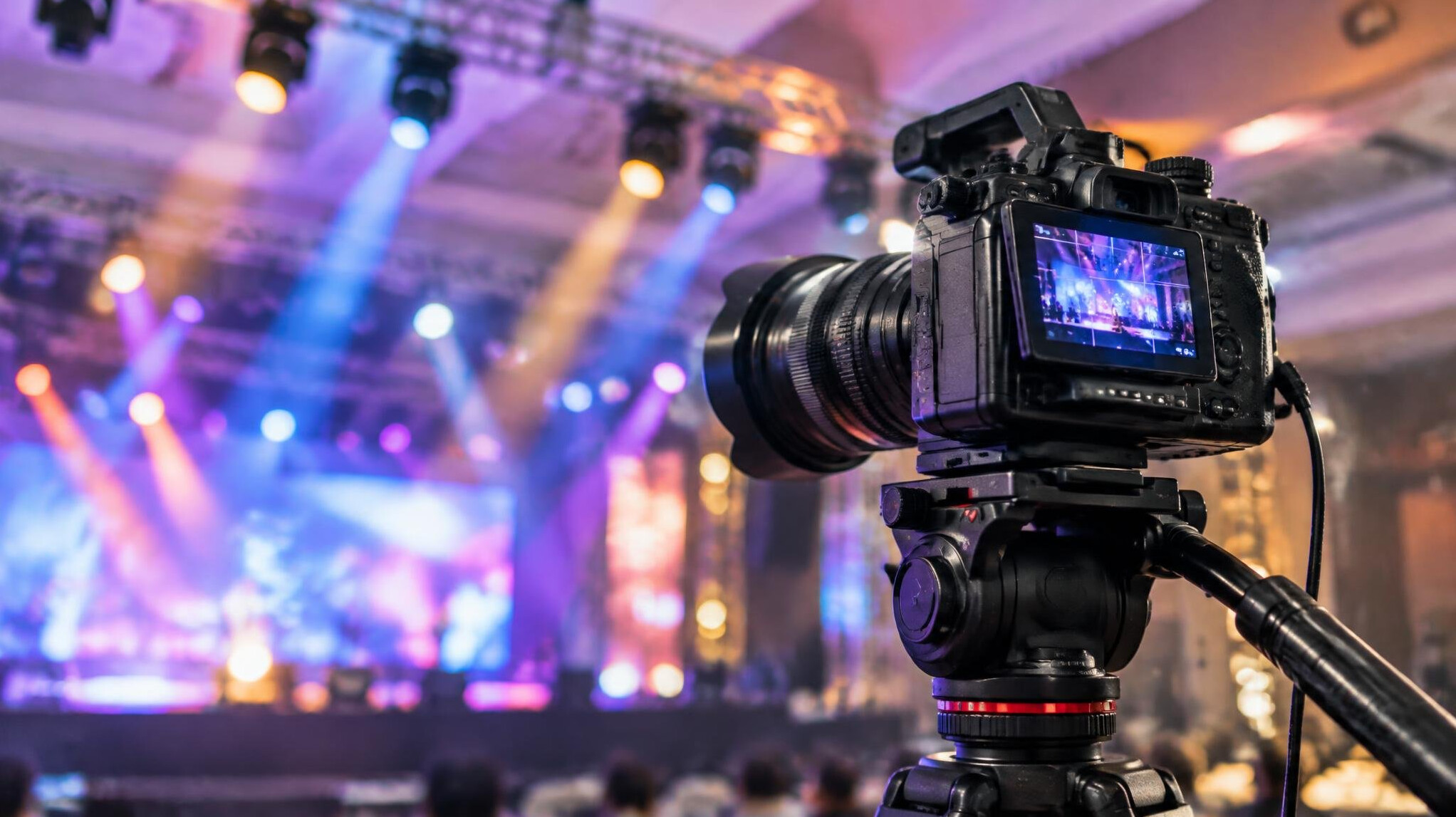 Camera positioned on a tripod with stage lighting in the background